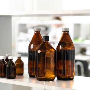 Close-up of brown glass bottles on a shelf in a laboratory environment.