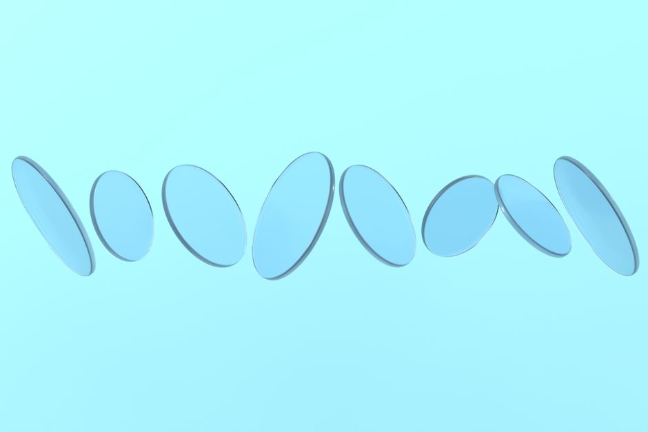 Abstract arrangement of transparent blue glass discs floating against a pastel blue backdrop.